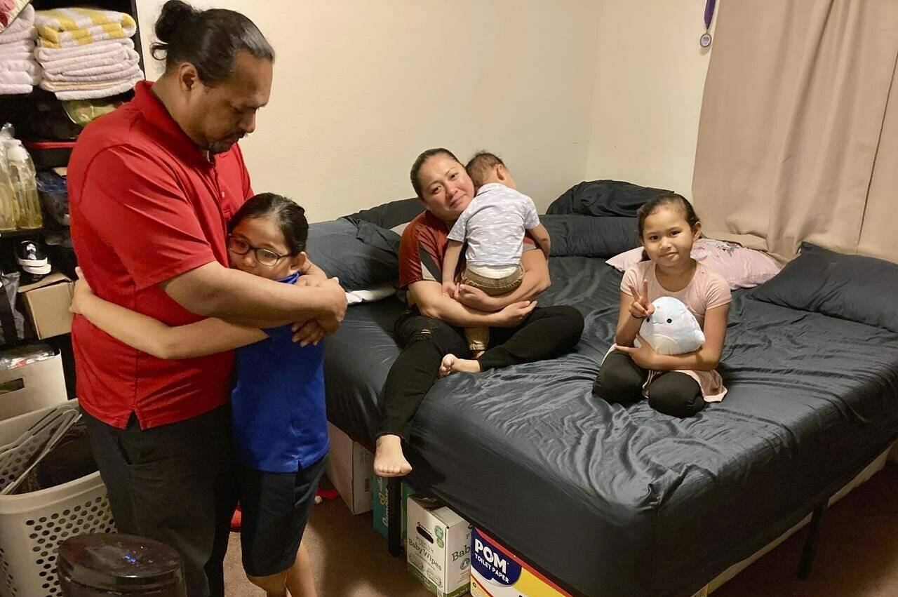 The five-member Purdy family gather in one of two bedrooms they share in a house they rent with extended family in Kapolei, Hawaii, on Wednesday, Dec. 14, 2022. The family moved to Las Vegas in 2017 to escape Hawaii’s high cost of living and returned last year and share two bedrooms in a home they rent with extended family. Native Hawaiians, like the Purdys, who have been priced out of Hawaii are finding more affordable places to live in cities like Las Vegas. (AP Photo/Jennifer Sinco Kelleher)