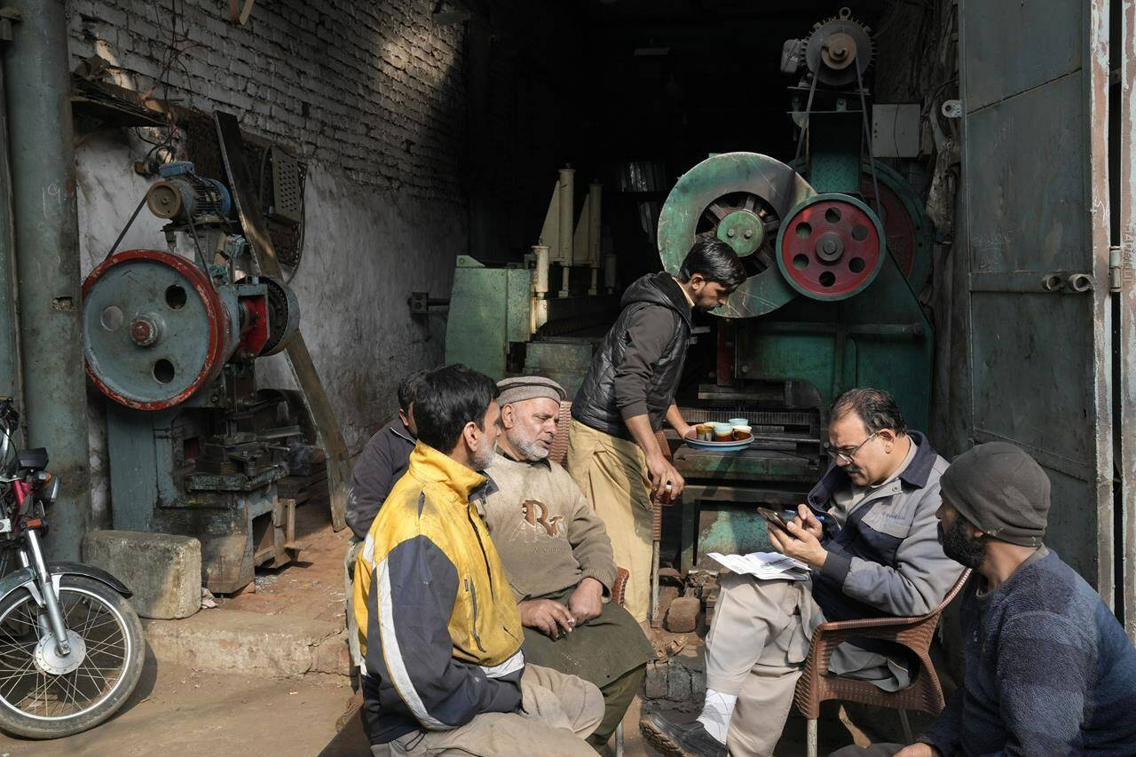 Workers wait for electricity outside their workshop following a power breakdown across the country, in Lahore, Pakistan, Monday, Jan. 23, 2023. Much of Pakistan was left without power for several hours on Monday morning as an energy-saving measure by the government backfired. The outage spread panic and raised questions about the cash-strapped government’s handling of the crisis. (AP Photo/K.M. Chaudary)