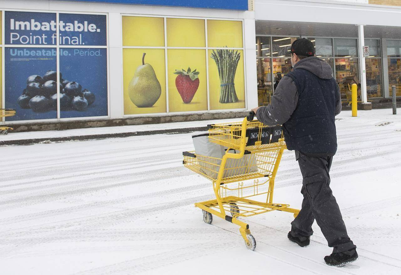 A man pushes a shopping cart towards a closed grocery store in Montreal, Sunday, Jan. 9, 2022. A new report says discount grocery stores are set to outperform conventional supermarkets in 2023. THE CANADIAN PRESS/Graham Hughes