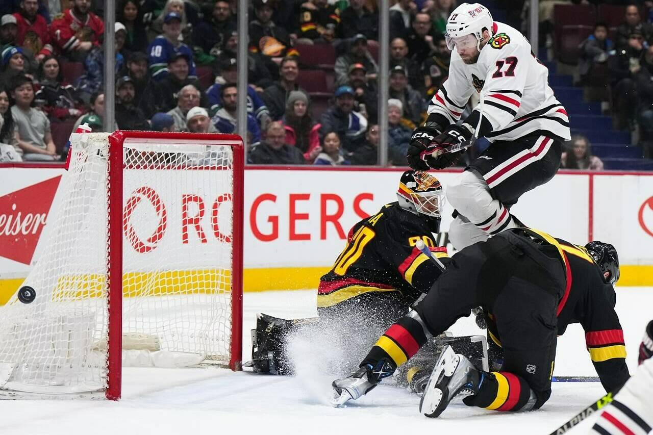 Chicago Blackhawks’ Jason Dickinson (17) jumps over Vancouver Canucks goalie Collin Delia (60) and Tyler Myers to avoid a collision during the second period of an NHL hockey game in Vancouver, on Tuesday, January 24, 2023. THE CANADIAN PRESS/Darryl Dyck