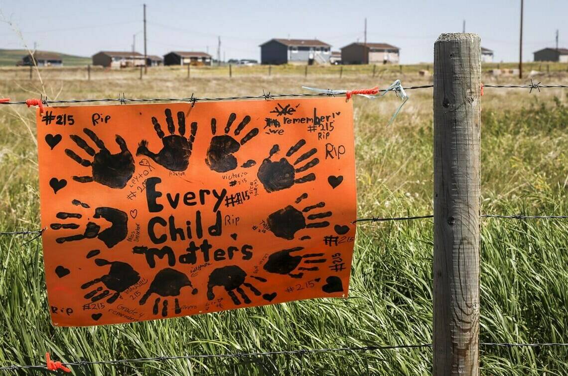 A sign commemorating victims of residential schools is attached to a fence line in front of homes east of Calgary near Gliechen, Alta., Tuesday, June 29, 2021. A new report from a group looking into children that died and went missing at an Alberta residential school says unpasteurized milk was responsible for the deaths of Indigenous children at the institution. THE CANADIAN PRESS/Jeff McIntosh