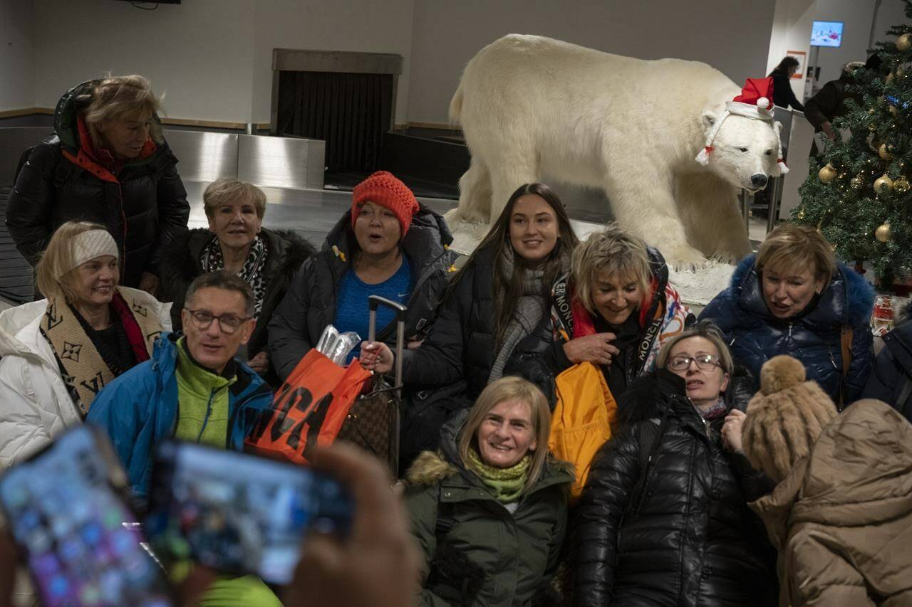Tourists take pictures with a stuffed polar bear upon arriving to Longyearbyen airport, Norway, Friday, Jan. 6, 2023. (AP Photo/Daniel Cole)