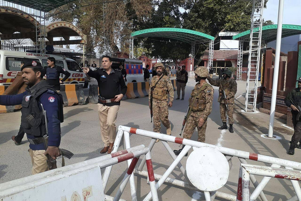 Army soldiers and police officers clear the way for ambulances rushing toward a bomb explosion site, at the main entry gate of police offices, in Peshawar, Pakistan, Monday, Jan. 30, 2023. A powerful bomb went off Monday near a mosque and police offices in the northwestern Pakistani city of Peshawar, killing at least a few people and wounding some 70 worshippers, police and government officials said. (AP Photo/Muhammad Sajjad)