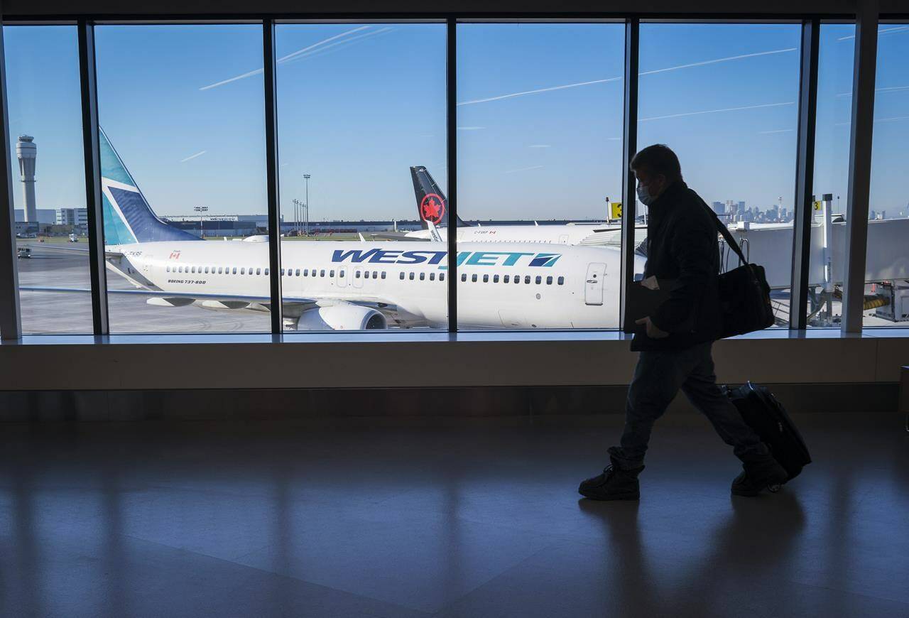 Passengers walk past Air Canada and WestJet planes at Calgary International Airport in Calgary, Alta., Wednesday, Aug. 31, 2022. THE CANADIAN PRESS/Jeff McIntosh