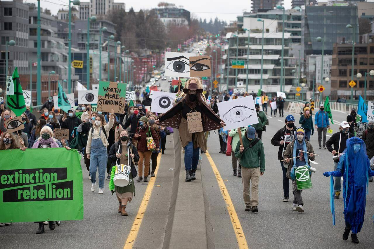 People taking part in an Extinction Rebellion protest against old-growth logging march onto the empty Cambie Bridge, in Vancouver, B.C., Saturday, March 27, 2021. A man who took part in four traffic-stopping protests in Metro Vancouver in an effort to save old-growth forests has been given a conditional sentence and six months probation. THE CANADIAN PRESS/Darryl Dyck