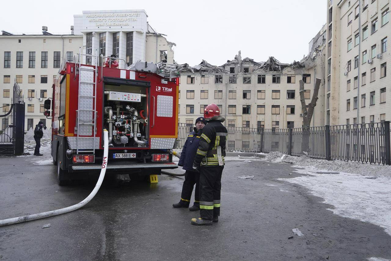Emergency workers stand in front of Kharkiv National Academy of Urban Economy which was hit by a Russian rocket, in the city center of Kharkiv, Ukraine, Sunday, Feb. 5, 2023. (AP Photo/Andrii Marienko)