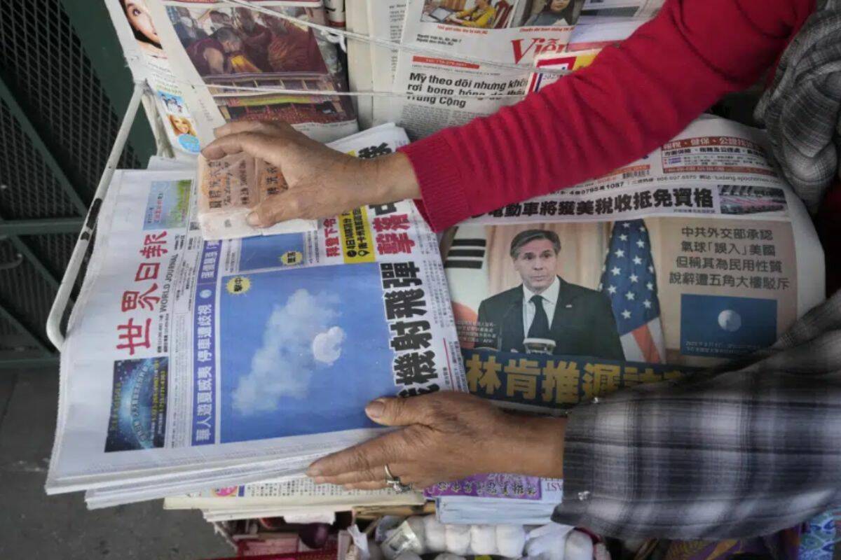 Business owner "Annie" weights down copies of the Chinese Daily News newspaper showcasing pictures of a suspected Chinese spy balloon, in the Chinatown district of Los Angeles Sunday, Feb. 5, 2023. The balloon's presence in the sky above the United States before a military jet shot it down over the Atlantic Ocean with a missile Saturday has further strained U.S.- China ties. (AP Photo/Damian Dovarganes)