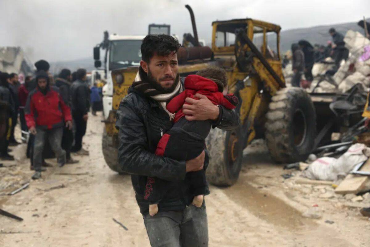 A man carries the body of an earthquake victim in the Besnia village near the Turkish border, Idlib province, Syria, Monday, Feb. 6, 2023. A powerful earthquake has caused significant damage in southeast Turkey and Syria and many casualties are feared. Damage was reported across several Turkish provinces, and rescue teams were being sent from around the country. (AP Photo/Ghaith Alsayed)