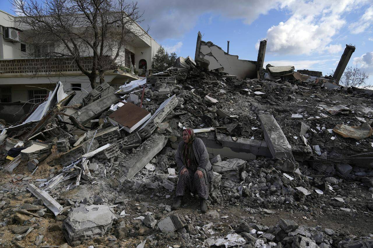 A woman sits on the rubble as emergency rescue teams search for people under the remains of destroyed buildings in Nurdagi town on the outskirts of Osmaniye city southern Turkey, Tuesday, Feb. 7, 2023. Ottawa says Canada will contribute $10 million to earthquake relief efforts in Turkey and Syria as part of an initial aid package. THE CANADIAN PRESS/AP/Khalil Hamra