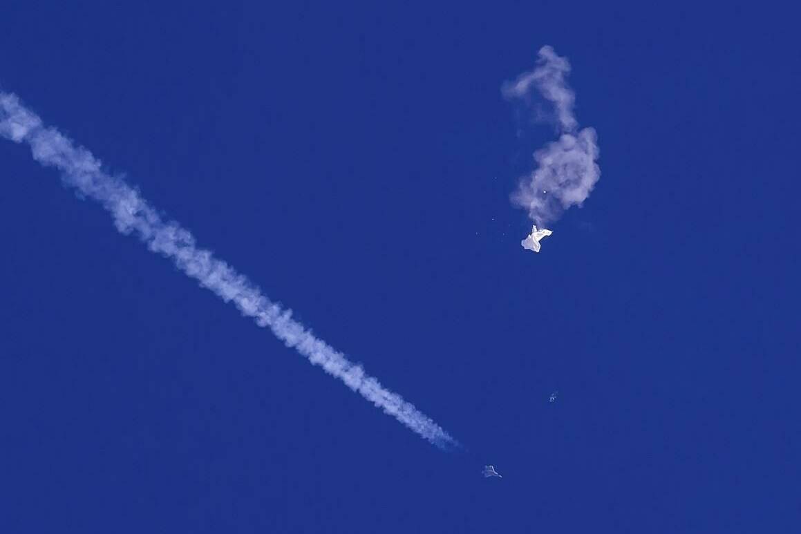 In this photo provided by Chad Fish, the remnants of a large balloon drift above the Atlantic Ocean, just off the coast of South Carolina, with a fighter jet and its contrail seen below it, Feb. 4, 2023. China on Thursday, Feb. 9, 2023, said U.S. accusations that a downed Chinese balloon was part of an extensive surveillance program amount to “information warfare against China.” (Chad Fish via AP, File)