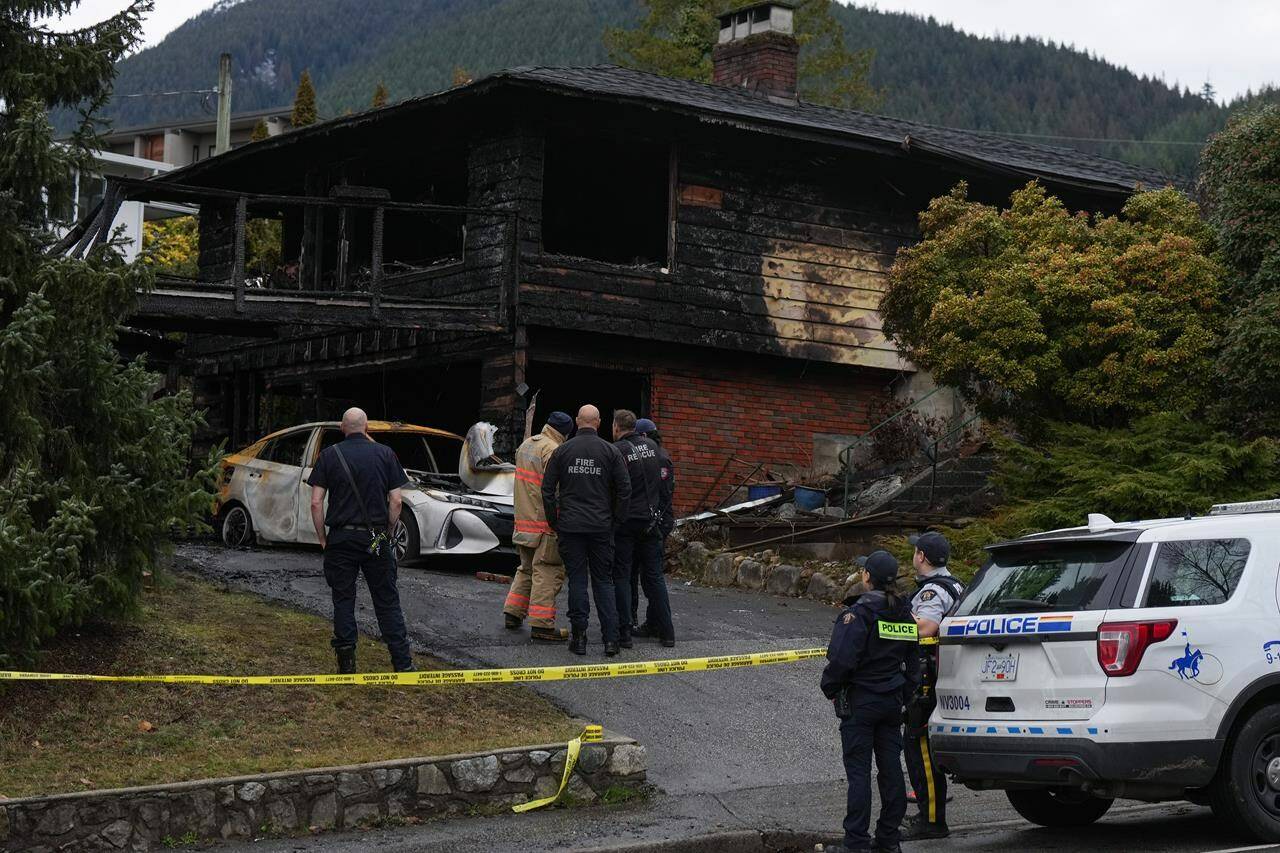 Firefighters and RCMP officers are seen outside a house where two people died in an early morning fire, in North Vancouver, B.C., on Thursday, Feb. 9, 2023. Flags in the City of North Vancouver are at half-mast to mark a former councillor’s death in the house fire. THE CANADIAN PRESS/Darryl Dyck