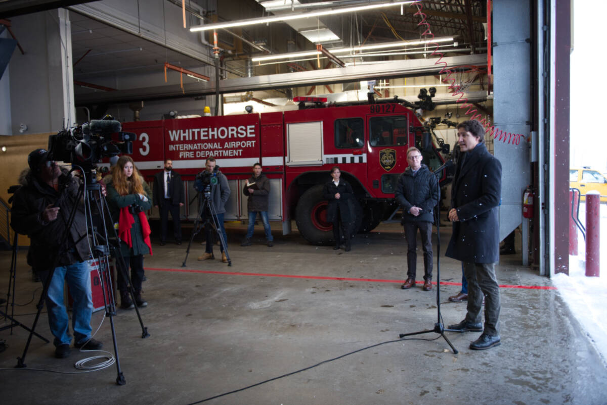 Prime Minister Justin Trudeau (front right) answers questions from reporters at the Whitehorse airport firehall on Feb. 13. (Gabrielle Plonka/Yukon News)