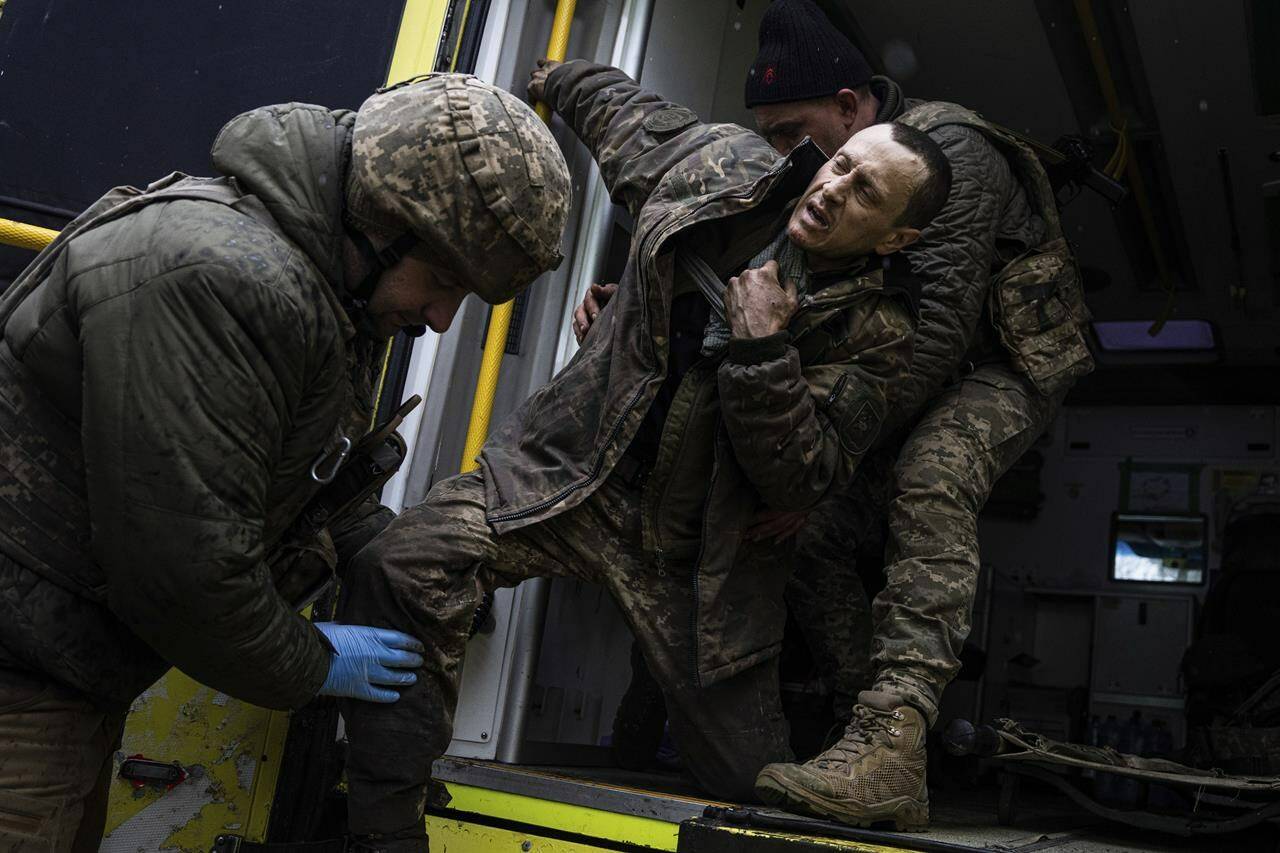 Ukrainian military medics help their wounded comrade to get out from an ambulance after arriving from the battlefield to the field hospital near Bakhmut, Ukraine, Sunday, Feb. 26, 2023. (AP Photo/Evgeniy Maloletka)