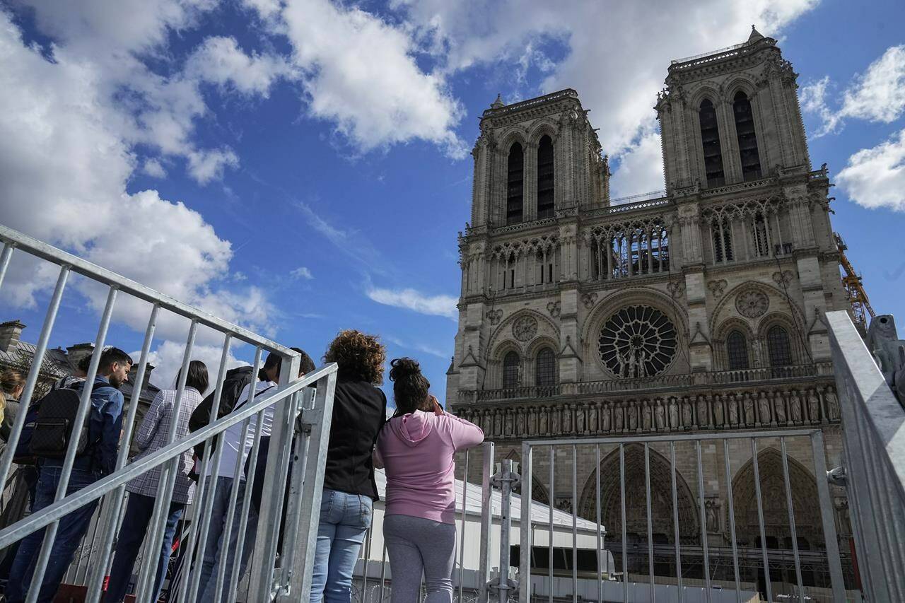 FILE - People have a close look of Notre Dame cathedral as they visit the rebuilding site during Heritage Day in Paris, Saturday, Sept. 17, 2022. France’s Notre Dame Cathedral’s reconstruction is progressing enough to allow its reopening to visitors and masses at the end of next year, less than six years after the after the shocking fire that tore through its roof, French officials said as an exhibit pays tribute to hundreds of artisans working on it. (AP Photo/Michel Euler, File)