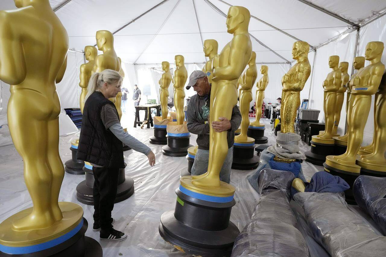 Antje Menikheim, left, lead scenic painter for Sunday’s 95th Academy Awards, and scenic artist Michael Thomas prepare Oscar statues for the event, Wednesday, March 8, 2023, near the Dolby Theatre in Los Angeles. (AP Photo/Chris Pizzello)