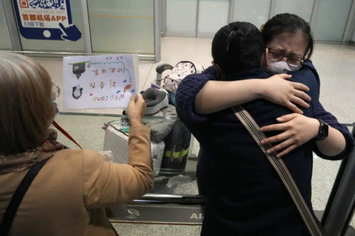 A woman hugs another returning on one of the few overseas flight arriving at the Beijing Capital International Airport in Beijing, Tuesday, March 14, 2023. China will reopen its borders to tourists and resume issuing all visas Wednesday after a three-year halt during the pandemic as it sought to boost its tourism and economy. (AP Photo/Ng Han Guan)