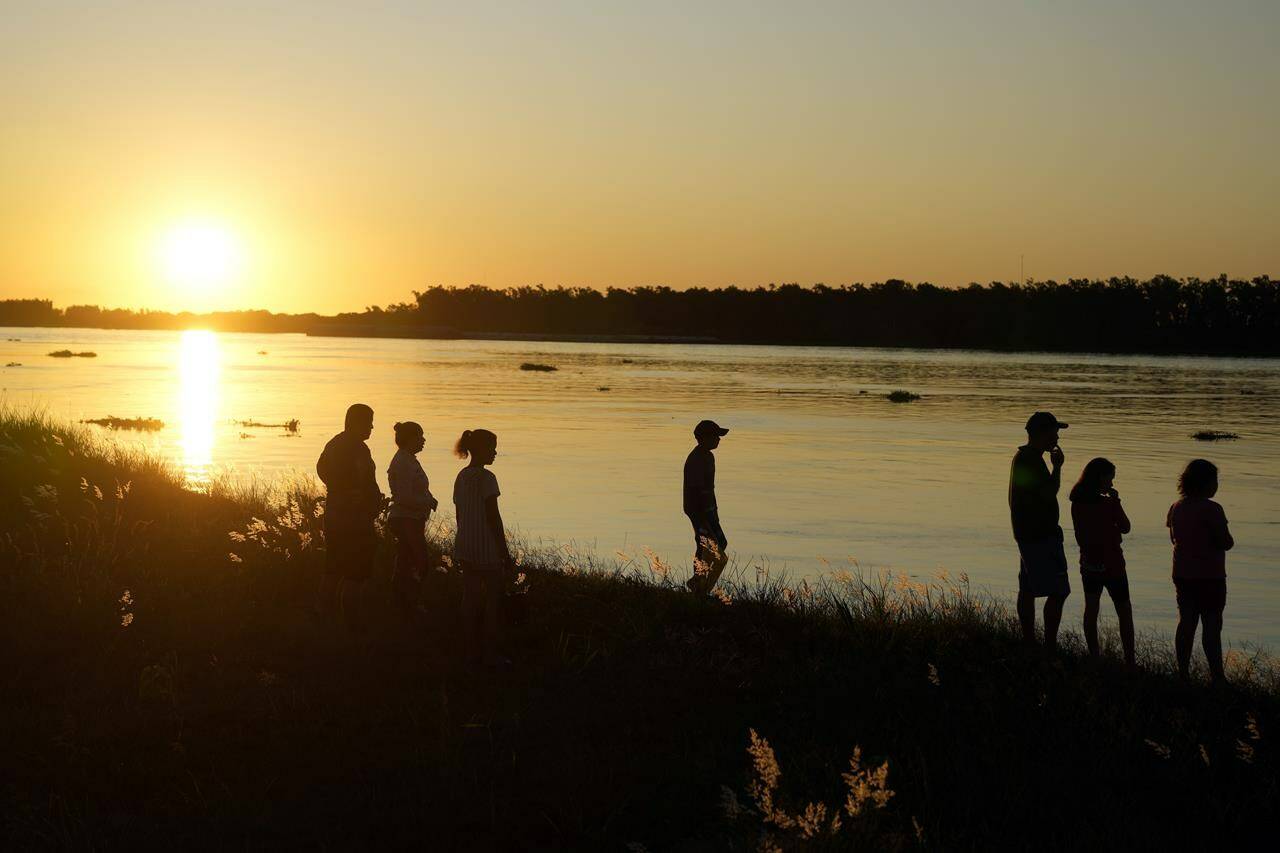 People gather on the shore of the Paraguay River in Asuncion, Paraguay, Sunday, March 19, 2023. (AP Photo/Jorge Saenz)
