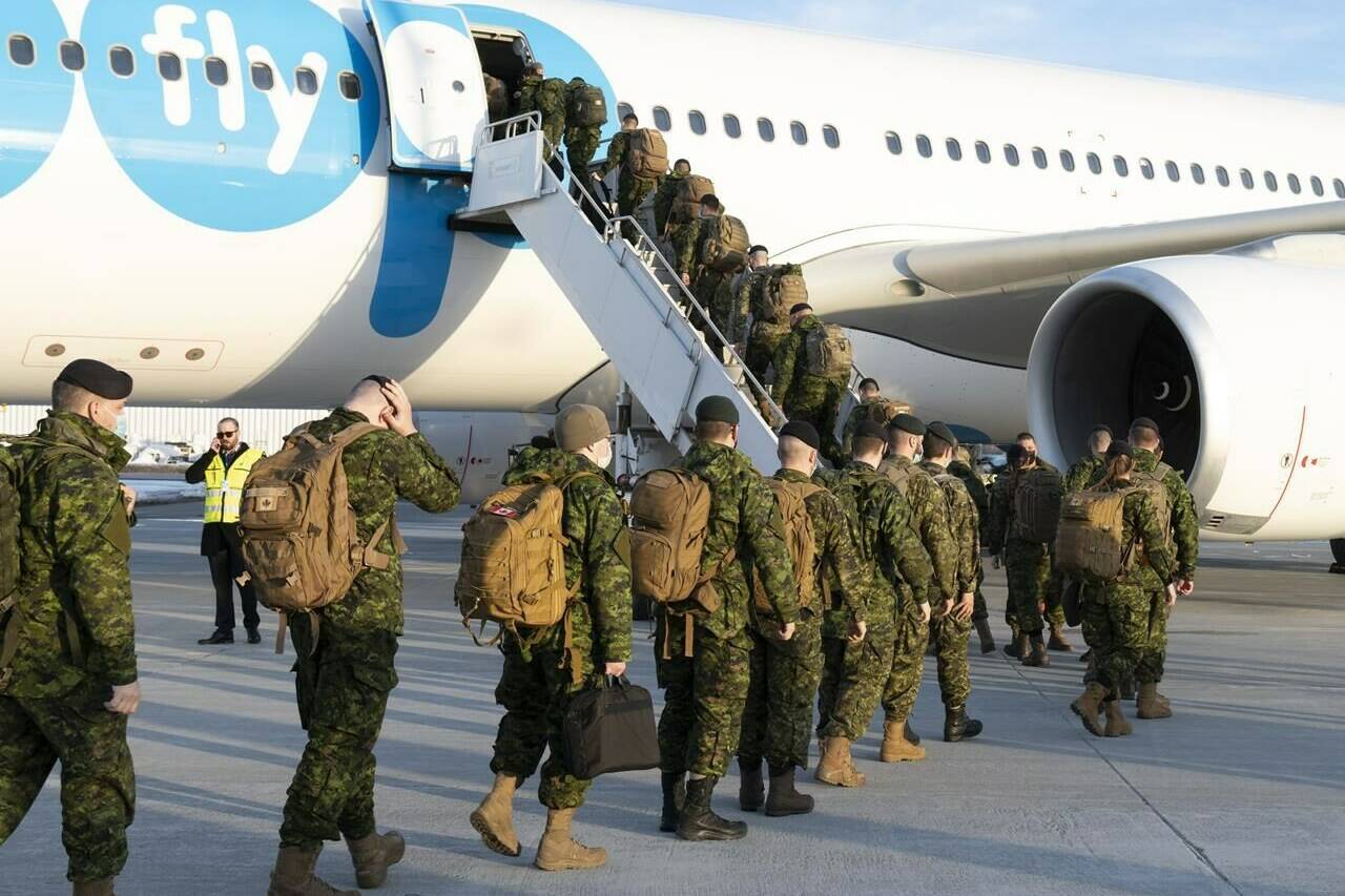 Members of the 5e Regiment d’artillerie legere du Canada board an aircraft heading for Latvia, in Quebec City, Wednesday, March 23, 2022. The Canadian Armed Forces is under fire for its plan to cut thousands of troops off a cost-of-living allowance without much notice. THE CANADIAN PRESS/Jacques Boissinot