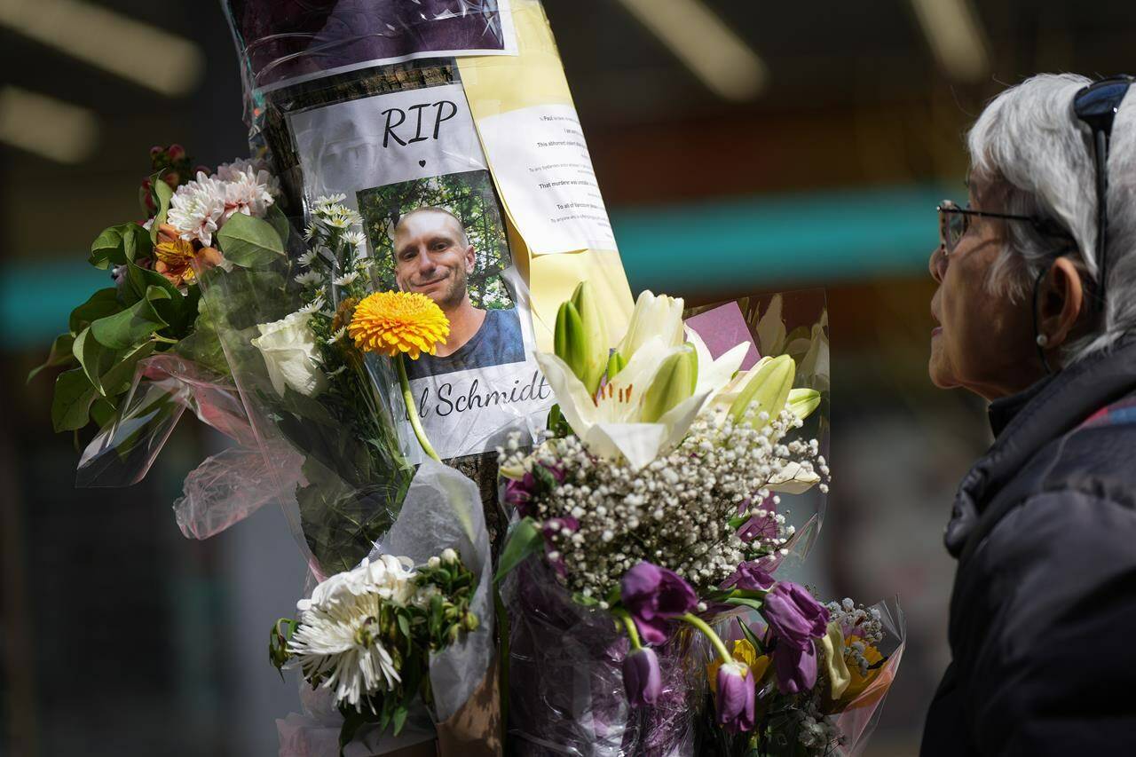 A woman pauses at a makeshift memorial for Paul Stanley Schmidt, 37, who died after being stabbed on Sunday outside a Starbucks in downtown Vancouver, on Wednesday, March 29, 2023. Vancouver police say Inderdeep Singh Gosal, 32, has been charged with second-degree murder and investigators do not believe the suspect and victim knew each other. THE CANADIAN PRESS/Darryl Dyck