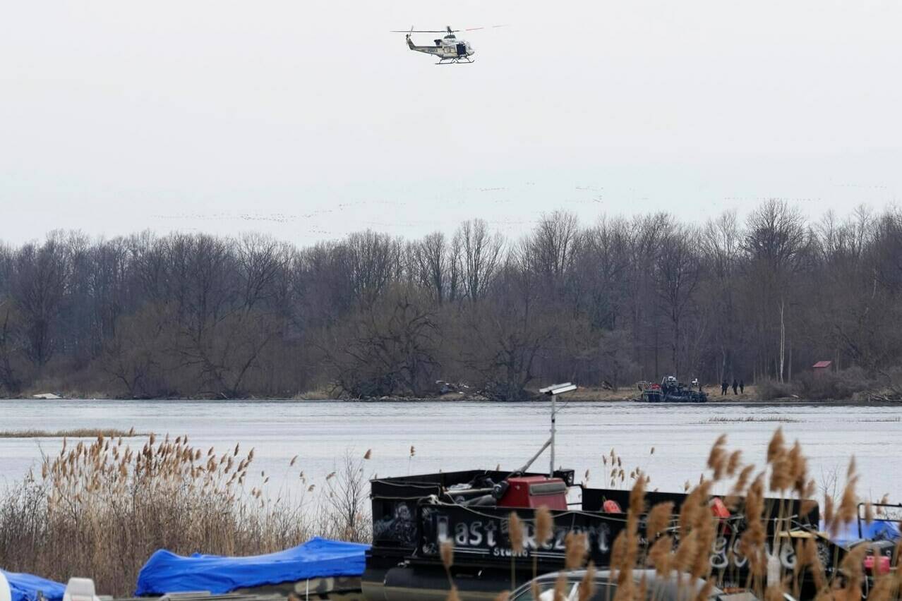 A police helicopter searches the area in Akwesasne, Que., Friday, March 31, 2023. Authorities in the Mohawk Territory of Akwesasne say the bodies of eight migrants of Indian and Romanian descent were pulled from the river Thursday. THE CANADIAN PRESS/Ryan Remiorz