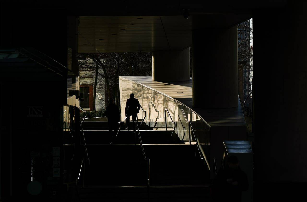 A man is silhouetted while walking up steps as sunlight reflects off a metallic wall outside an office tower in downtown Vancouver, on Thursday, March 30, 2023. Avison Young says Vancouver’s downtown office vacancy rate hit 10 per cent for the first time in almost 20 years. THE CANADIAN PRESS/Darryl Dyck
