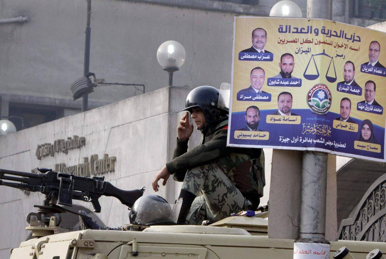 An Egyptian soldier sits on his armoured vehicle in front of a Freedom and Justice Party Arabic-language poster supporting Muslim Brothehood candidates outside a ballot counting centre in Giza, Egypt, Friday, Dec. 16, 2011. The party and the Brotherhood have since been outlawed. Egyptian asylum seekers spoke Monday alongside NDP MP Don Davies at his constituency office in Vancouver, decrying the CBSA’s treatment of recent claimants affiliated with the Freedom and Justice Party and the potential denial of their refugee bids. THE CANADIAN PRESS/AP-Amr Nabil