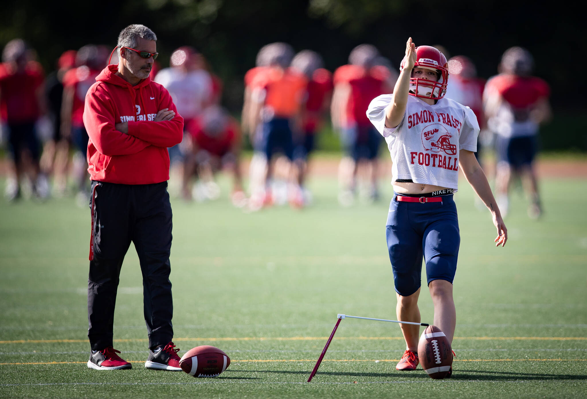 Simon Fraser University football team kicker Kristie Elliott, who had recently become the first Canadian woman to play and score in a college football game, lines up a kick as coach Jerome Erdman watches during team practice in Burnaby, B.C., Tuesday, Sept. 21, 2021. THE CANADIAN PRESS/Darryl Dyck