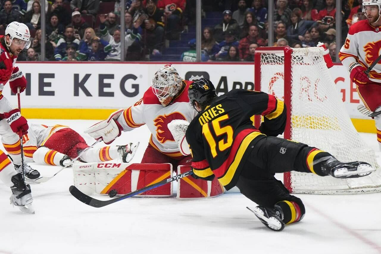 Calgary Flames goalie Jacob Markstrom, back centre, stops Vancouver Canucks’ Sheldon Dries (15) during the second period of an NHL hockey game in Vancouver, on Saturday, April 8, 2023. THE CANADIAN PRESS/Darryl Dyck
