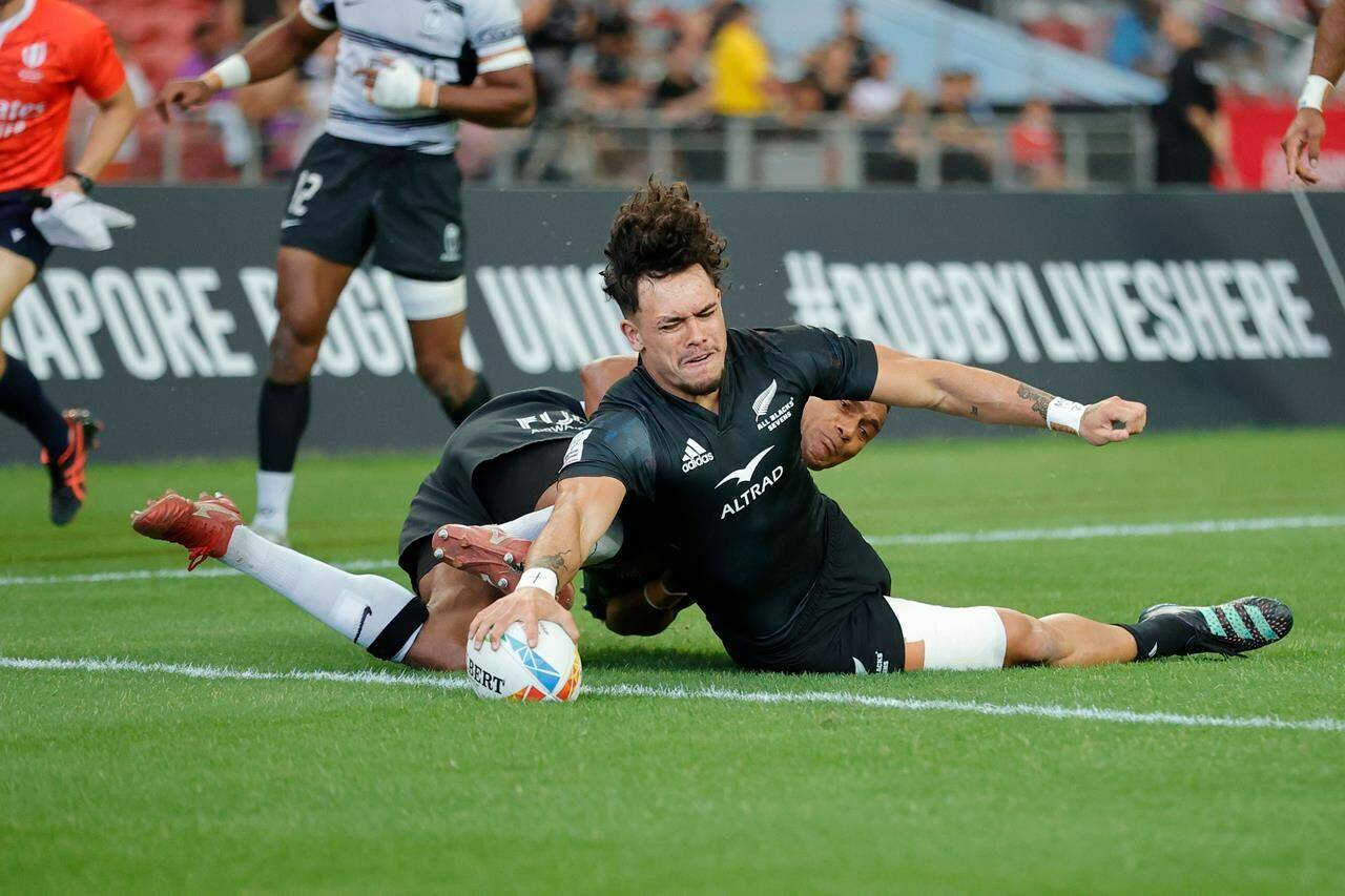 New Zealand’s Moses Leo, right, scores a try against Fiji at the HSBC Singapore Sevens at Singapore National Stadium, in Kallang, Singapore in a Sunday, April 9, 2023, handout photo. New Zealand won the tournament, becoming the first men’s team to qualify for the 2024 Paris Olympics. THE CANADIAN PRESS/HO-World Rugby, KLC fotos, Mike Lee