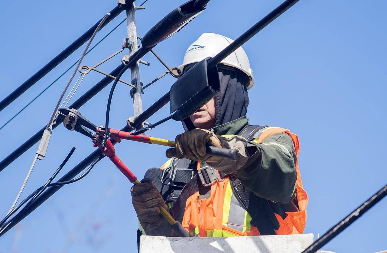 A Hydro worker works on a power line following an ice storm in Montreal, Friday, April 7, 2023. Hydro-Quebec says power has been restored to more than 90 per cent of the more than one million customers who lost electricity, but some of its remaining repairs may not be completed until Tuesday. THE CANADIAN PRESS/Graham Hughes