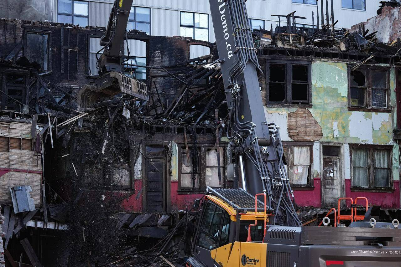 Debris falls to the ground as demolition resumes on the Winters Hotel after a body was found in the single room occupancy (SRO) building, in Vancouver, B.C., Friday, April 22, 2022. A woman who survived a fatal fire at the downtown Vancouver rooming hotel has filed a proposed class action lawsuit against the building’s owner, the non-profit organization that operated the residence, and the city’s fire department. THE CANADIAN PRESS/Darryl Dyck