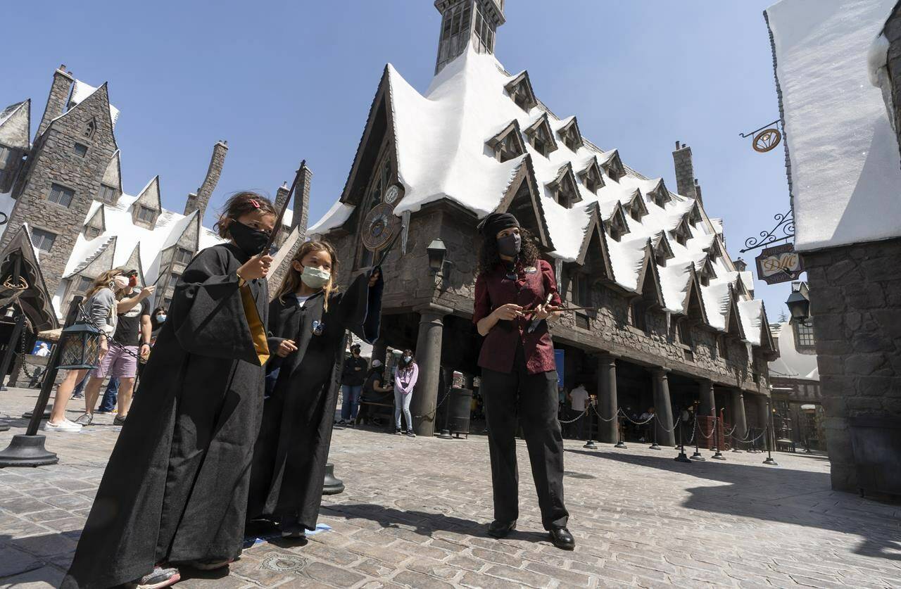 FILE - Campbell Chang, 6, and Juliana Single, 6, wear face masks as they cast their spells at Wizarding World of Harry Potter at Universal Studios Hollywood theme park in Los Angeles, on April 16, 2021. Warner Bros. Discovery is sticking with safe bet franchises that will likely lure viewers, including a “Harry Potter” series and a “Game of Thrones” prequel for its rebranded Max streaming service, the company announced Wednesday, April 12, 2023. (AP Photo/Damian Dovarganes, File)