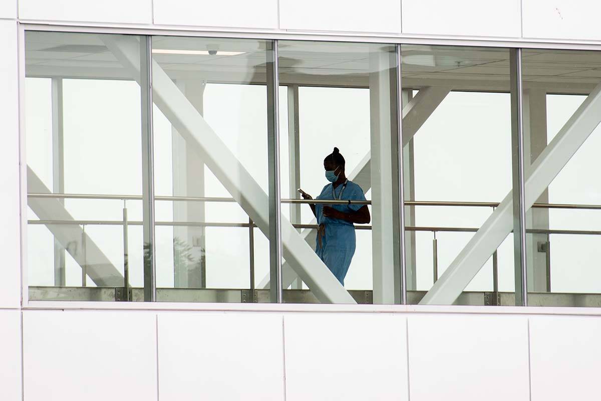 A health-care worker crosses a covered overhead walkway at a hospital in Montreal, Tuesday, August 17, 2021. In B.C., the human rights commissioner is opposing a provincial decision to end mask mandates in health-care settings. THE CANADIAN PRESS/Graham Hughes