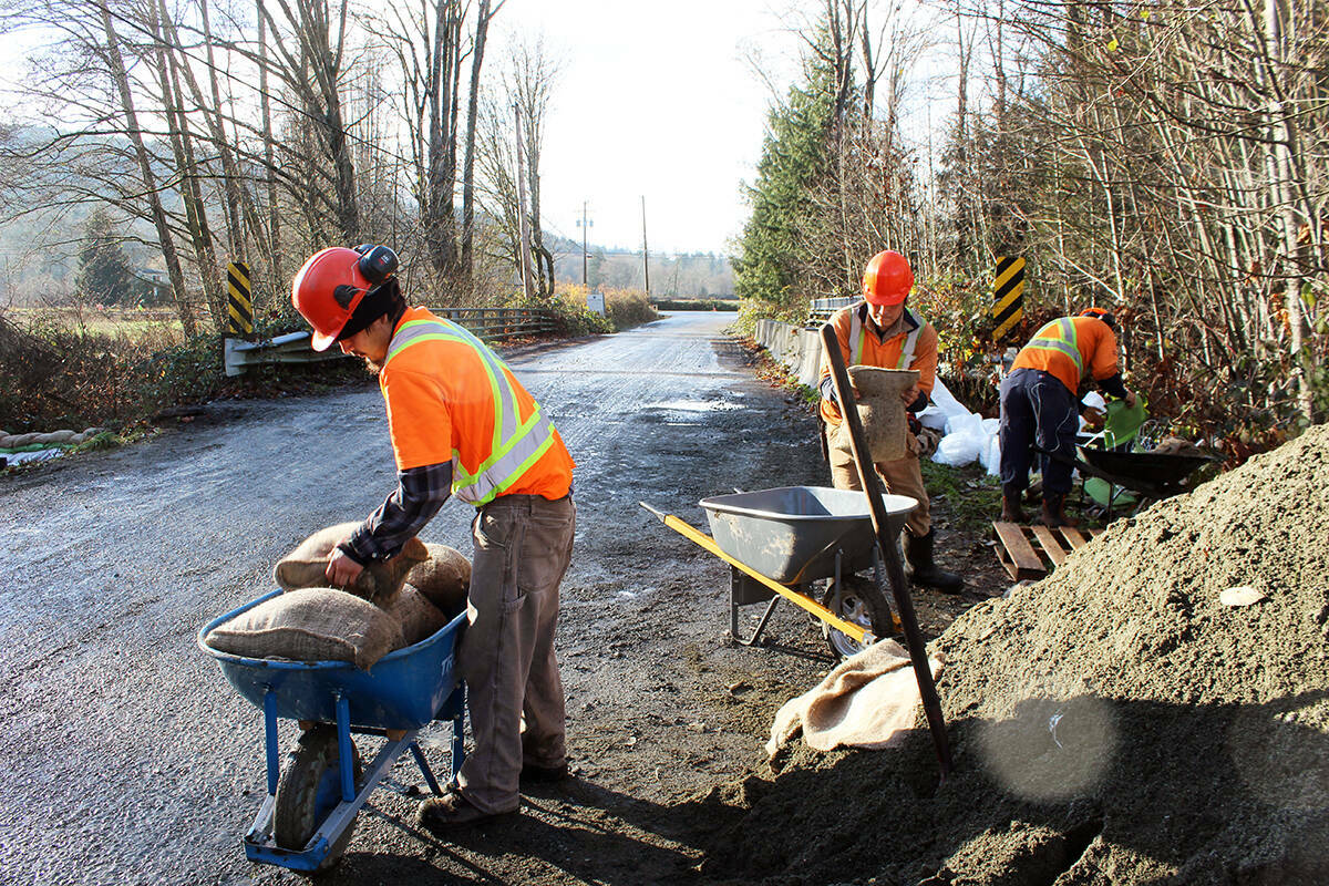 Wallace Antoine and Emanuel Sampson of Khowutzun Forest Services work on packing and hauling sandbags during Chemainus River flooding in November 2021. (Photo by Don Bodger)