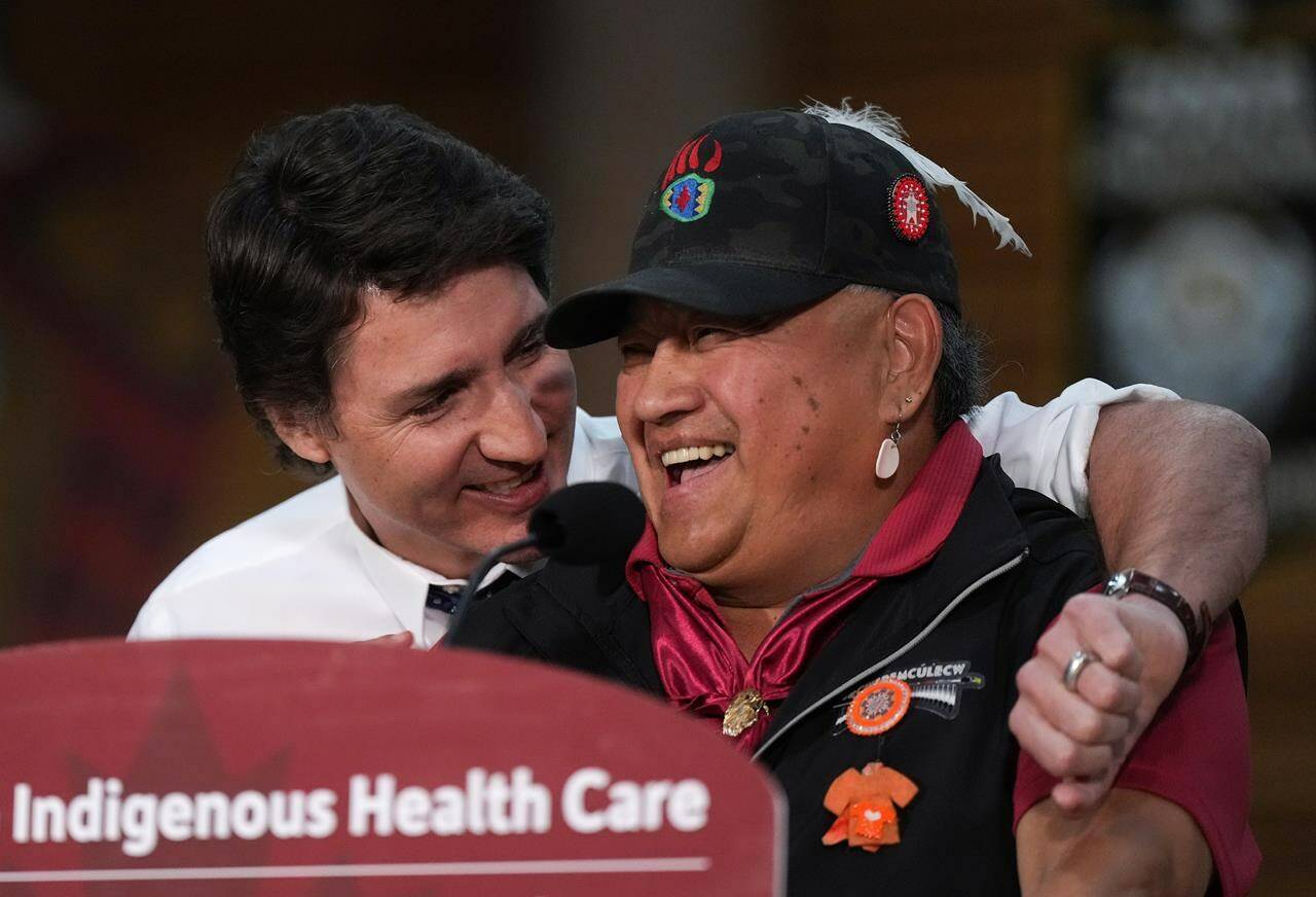 Prime Minister Justin Trudeau embraces Wayne Christian (Wenecwtsin), right, First Nations Health Authority Deputy Chair, as he jokes about knowing the prime minister’s late father, former prime minister Pierre Elliott Trudeau, while speaking during an announcement about First Nations health-care funding at the Squamish First Nation, in West Vancouver, B.C., on Friday, April 14, 2023. THE CANADIAN PRESS/Darryl Dyck