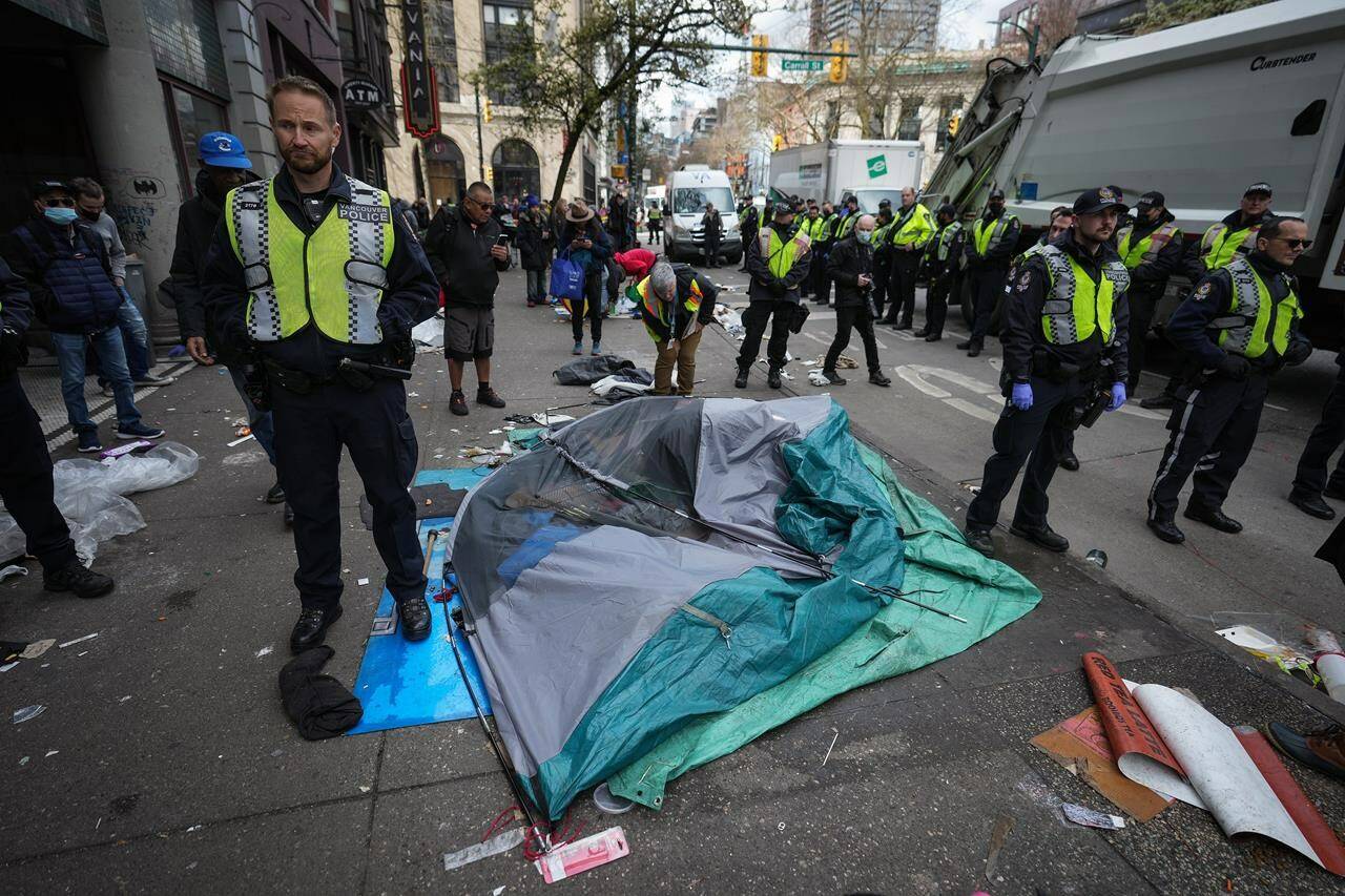 Vancouver police officers surround a tent with a person still inside as city workers clear an encampment on East Hastings Street in the Downtown Eastside of Vancouver, B.C., Wednesday, April 5, 2023. THE CANADIAN PRESS/Darryl Dyck