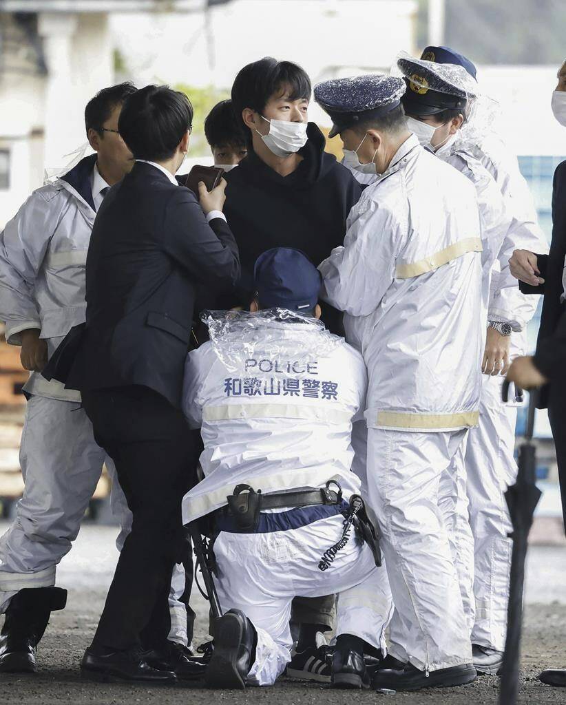 A man, center, who threw what appeared to be a smoke bomb, is caught at a port in Wakayama, western Japan Saturday, April 15, 2023. Japan’s NHK television reported Saturday that a loud explosion occurred at the western Japanese port during Prime Minister Fumio Kishida’s visit, but there were no injuries. (Kyodo News via AP)