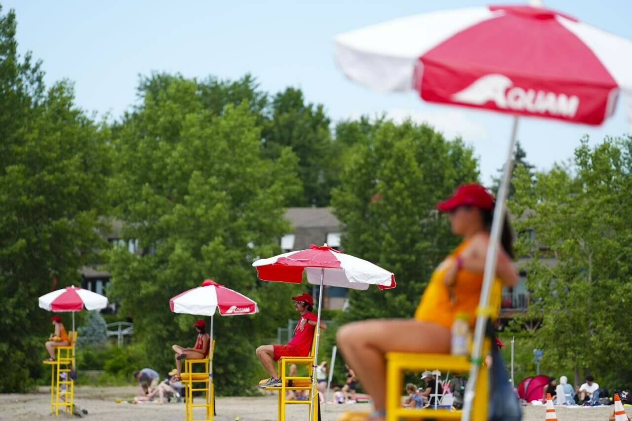 Lifeguards work at Brittany Beach of the Ottawa River in Ottawa, Friday, June 24, 2022. Ontario is proposing to lower the minimum age for lifeguards to 15, in part to address staff shortages many municipalities experienced last summer. THE CANADIAN PRESS/Sean Kilpatrick