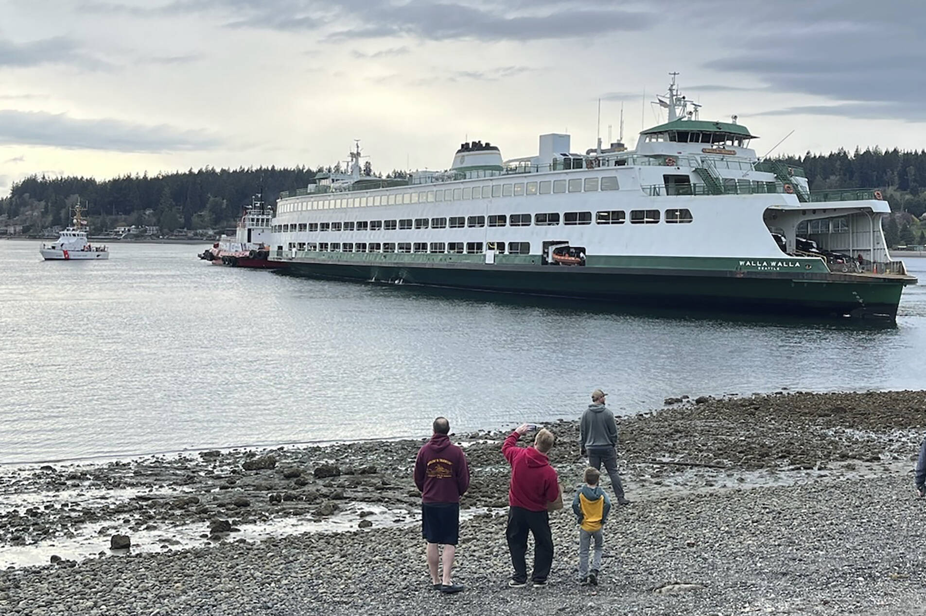 In this photo posted to the Washington state Department of Ecology website and taken by the U.S. Coast Guard, people watch as emergency crews respond to the Walla Walla passenger ferry, which ran aground near Bainbridge Island west of Seattle, Saturday, April 15, 2023. (Lt. Cmdr. Brian Dykens/U.S. Coast Guard via AP)
