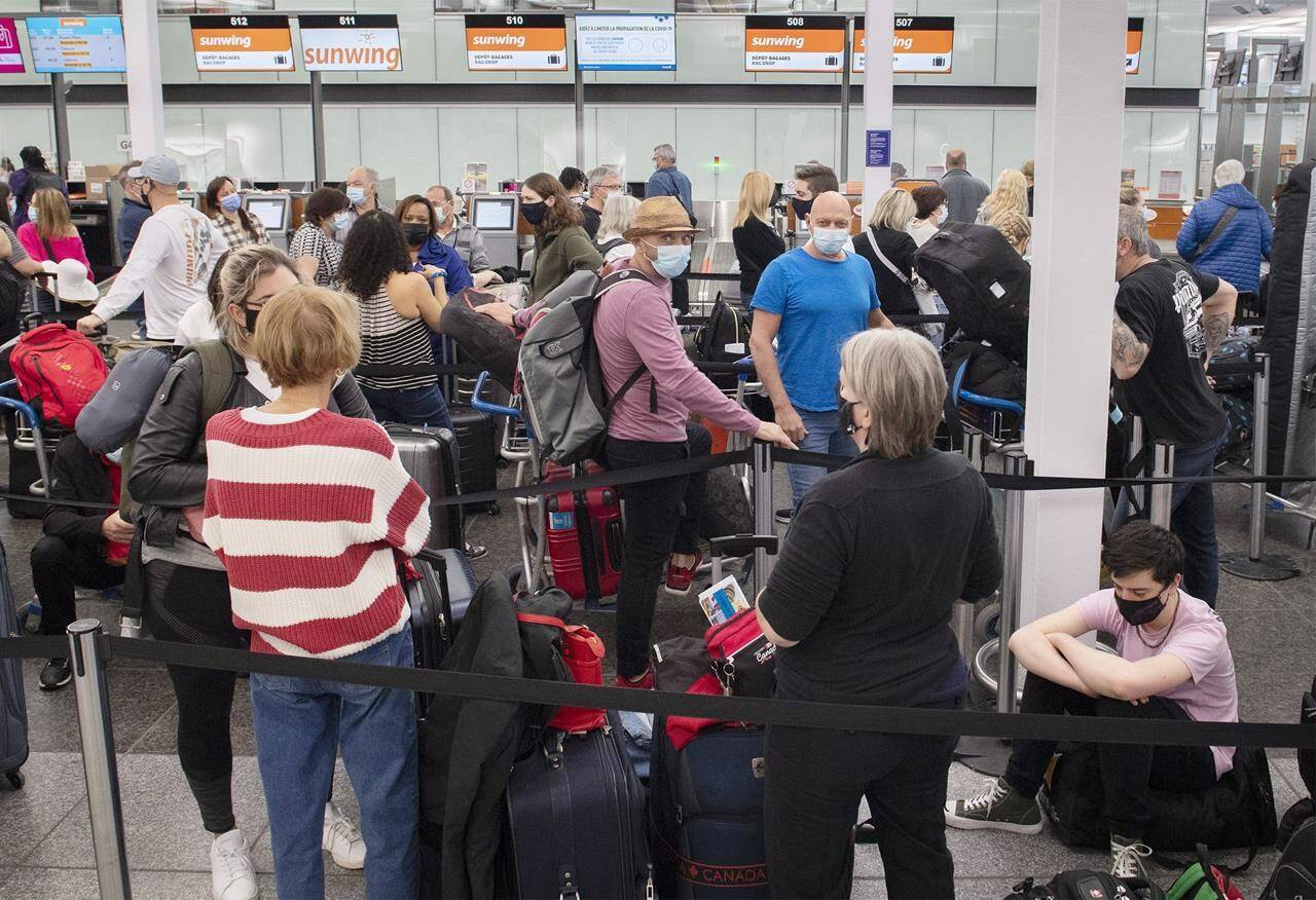 Travellers wait in line at a check-in desk at Trudeau Airport in Montreal, Wednesday, April 20, 2022. Canadian airports and airlines yielded a large number of flight delays last month, raising questions about their readiness for the summer travel rush. THE CANADIAN PRESS/Graham Hughes