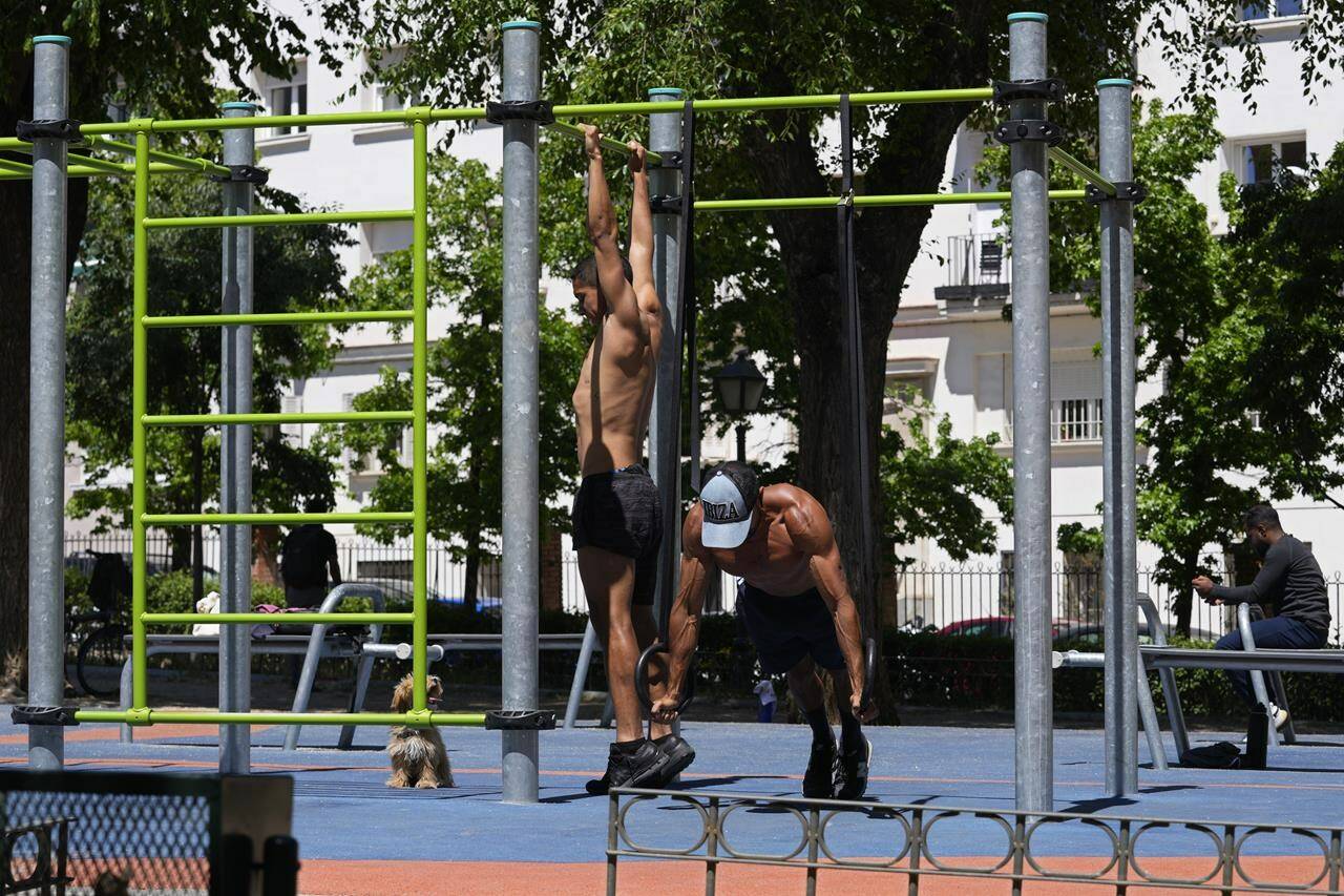 Two men exercise in a park in Madrid, Spain, Wednesday, April 26, 2023. Spain is experiencing summer temperatures in April as the country confronts another year of drought and the elevated risk of forest fires. (AP Photo/Paul White)