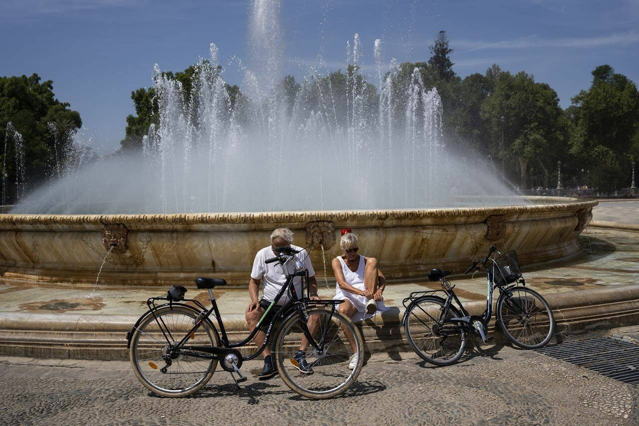 A couple rest by a fountain in Seville, Spain, Thursday, April 27, 2023. Spain’s national weather service said temperatures would “reach values typical of summer” across most of the country, with a high of 38 degrees Celsius (100 degrees Fahrenheit) forecast Thursday for the southern Guadalquivir Valley. (AP Photo/Santi Donaire)