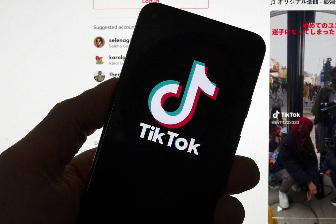 The TikTok logo is seen on a mobile phone in front of a computer screen which displays the TikTok home screen, Saturday, March 18, 2023, in Boston. THE CANADIAN PRESS/AP/Michael Dwyer