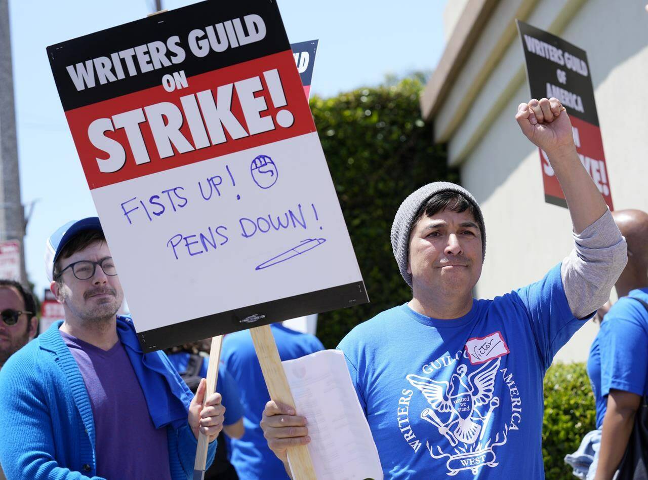 Writers Guild of America West member Victor Duenas pickets with others at an entrance to Paramount Pictures, Tuesday, May 2, 2023, in Los Angeles. The first Hollywood strike in 15 years began Tuesday as the economic pressures of the streaming era prompted unionized TV and film writers to picket for better pay outside major studios, a work stoppage that already is leading most late-night shows to air reruns. (AP Photo/Chris Pizzello)