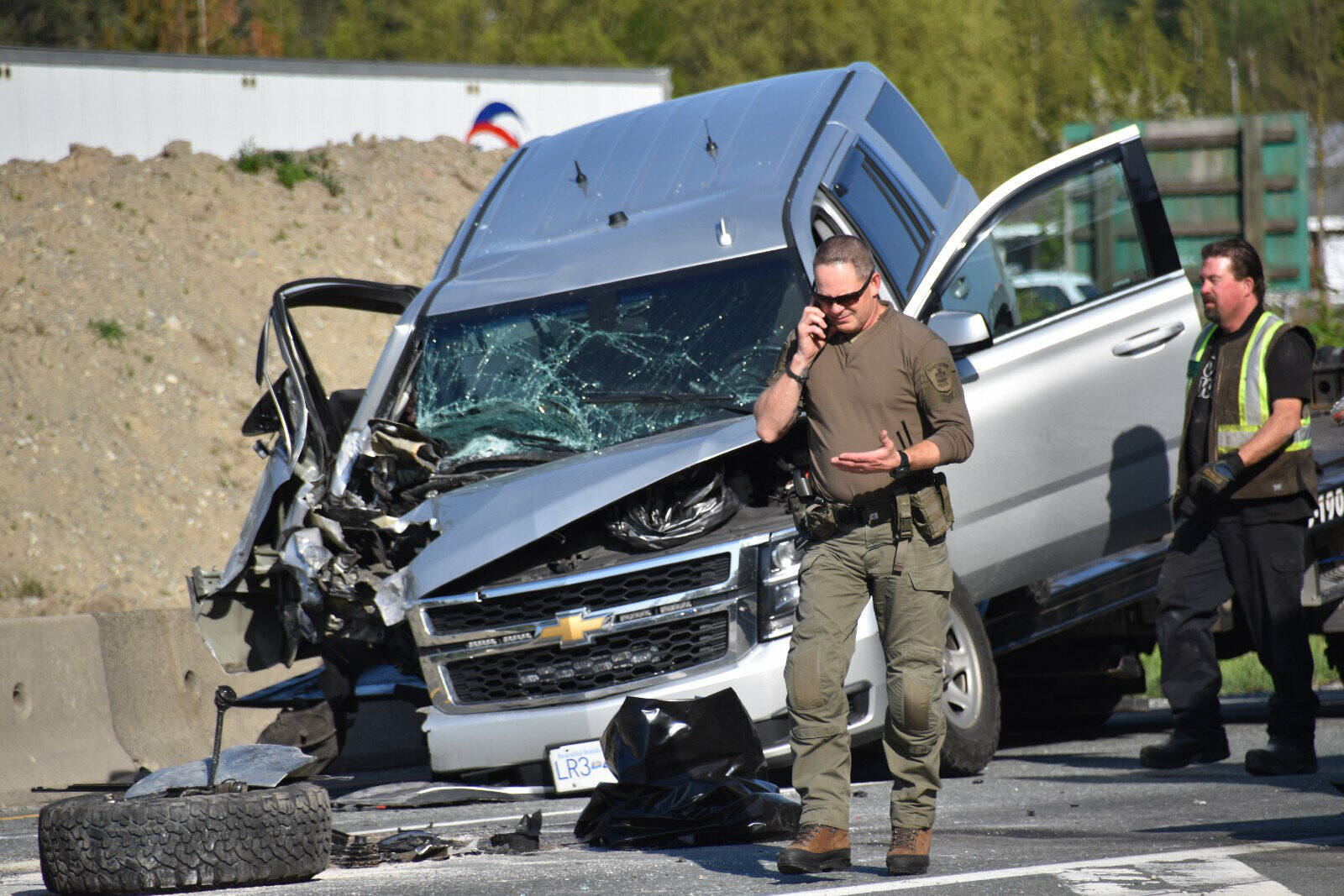 A member of the RCMP’s ERT team talks on the phone after an officer’s vehicle crashed into a dump truck on Highway 1 en route to a weapons call in Chilliwack on May 3, 2023. (Curtis Kreklau photo)