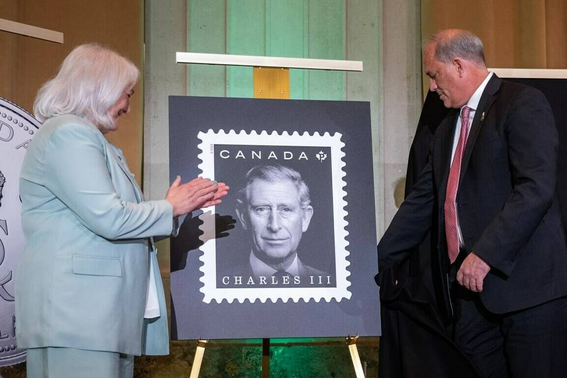 The official stamp is unveiled by Donald Booth, right, Canadian Secretary to the King, right, and Jo-Anne Polak, Senior Vice-President, Corporate and Employee Communication at Canada Post during coronation celebrations in honour of King Charles III in Ottawa, on Saturday, May 6, 2023. THE CANADIAN PRESS/Spencer Colby