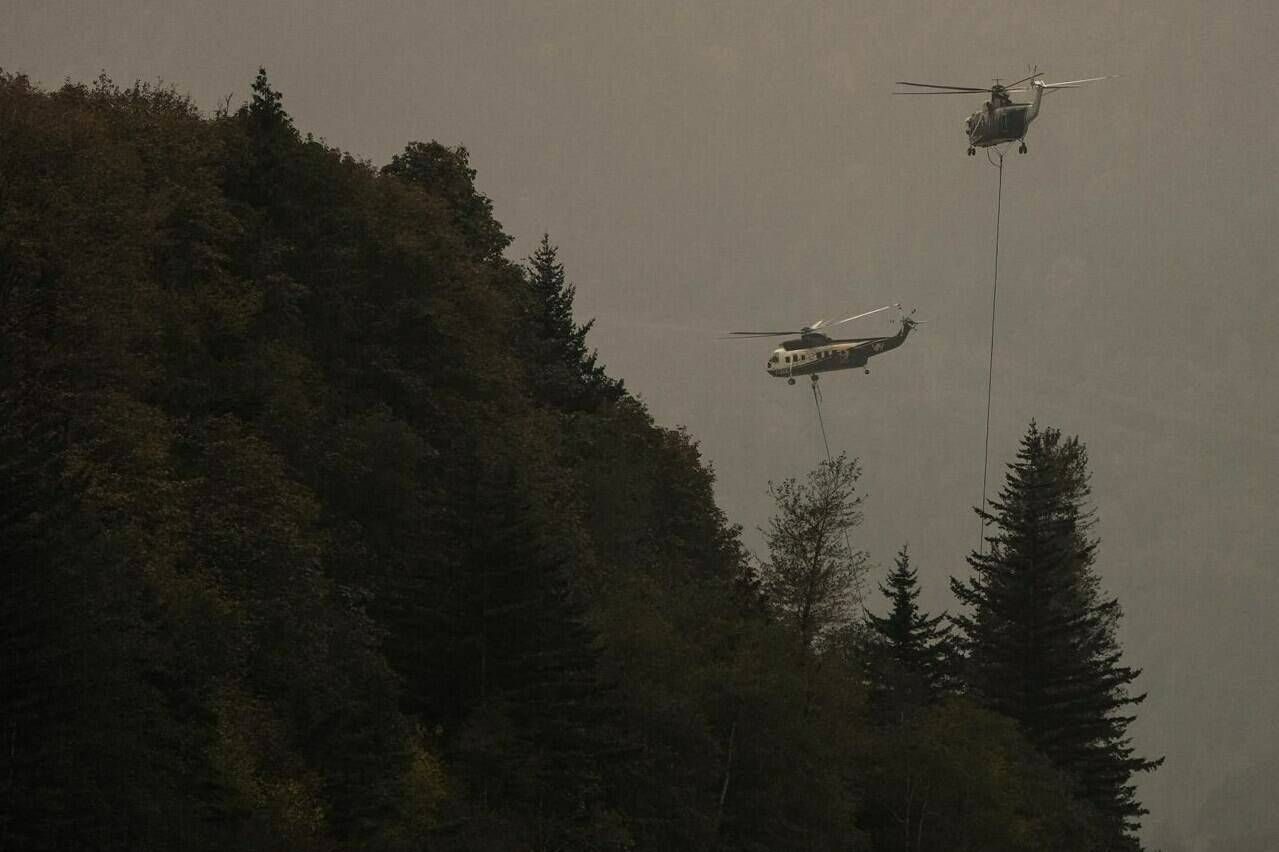 Helicopters with water buckets battle the Flood Falls Trail wildfire, in Hope, B.C., on Sept. 12, 2022. Three separate out-of-control wildfires burning near the boundary between British Columbia and Alberta, including two in the Peace River region, have prompted evacuation orders and an alert. THE CANADIAN PRESS/Darryl Dyck