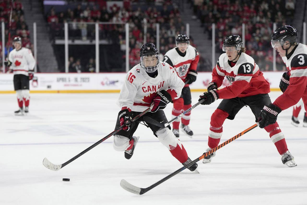 FILE - Canada’s Connor Bedard, left, skates past Austria’s Lukas Horl, right, and Luca Auer during the second period of a world junior hockey championships game Thursday, Dec. 29, 2022, in Halifax, Nova Scotia. The NHL draft lottery is drawn, determining which team gets the chance to select Connor Bedard with the No. 1 pick. The Anaheim Ducks, Columbus Blue Jackets and Chicago Blackhawks have the highest odds of landing the most anticipated top pick since Connor McDavid in 2015. (Darren Calabrese/The Canadian Press via AP, File)