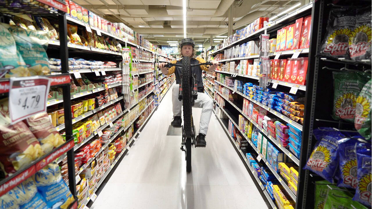 Trevor Meyer pops a wheelie in 49th Parallel Grocery while doing his grocery shopping in a scene from his winning BC Bike Race video. (Photo by Nick Clarke)