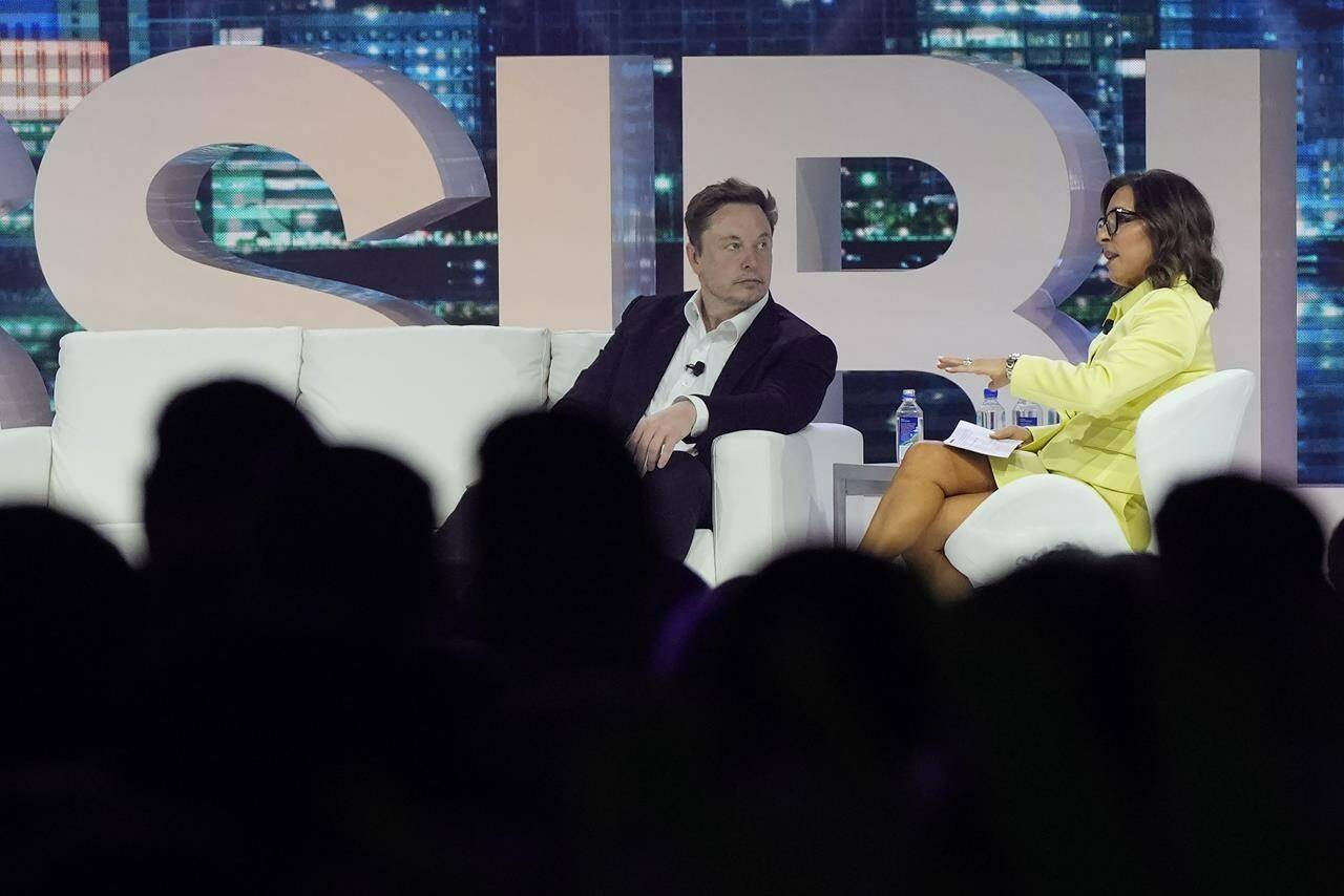 Twitter CEO Elon Musk, center, speaks with Linda Yaccarino, chairman of global advertising and partnerships for NBC, at the POSSIBLE marketing conference, Tuesday, April 18, 2023, in Miami Beach, Fla. (AP Photo/Rebecca Blackwell)